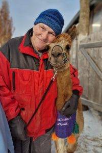 Ein Mann umarmt unser Wolfachtal Alpaka Sir Paul bei einem einer Alpakawanderung