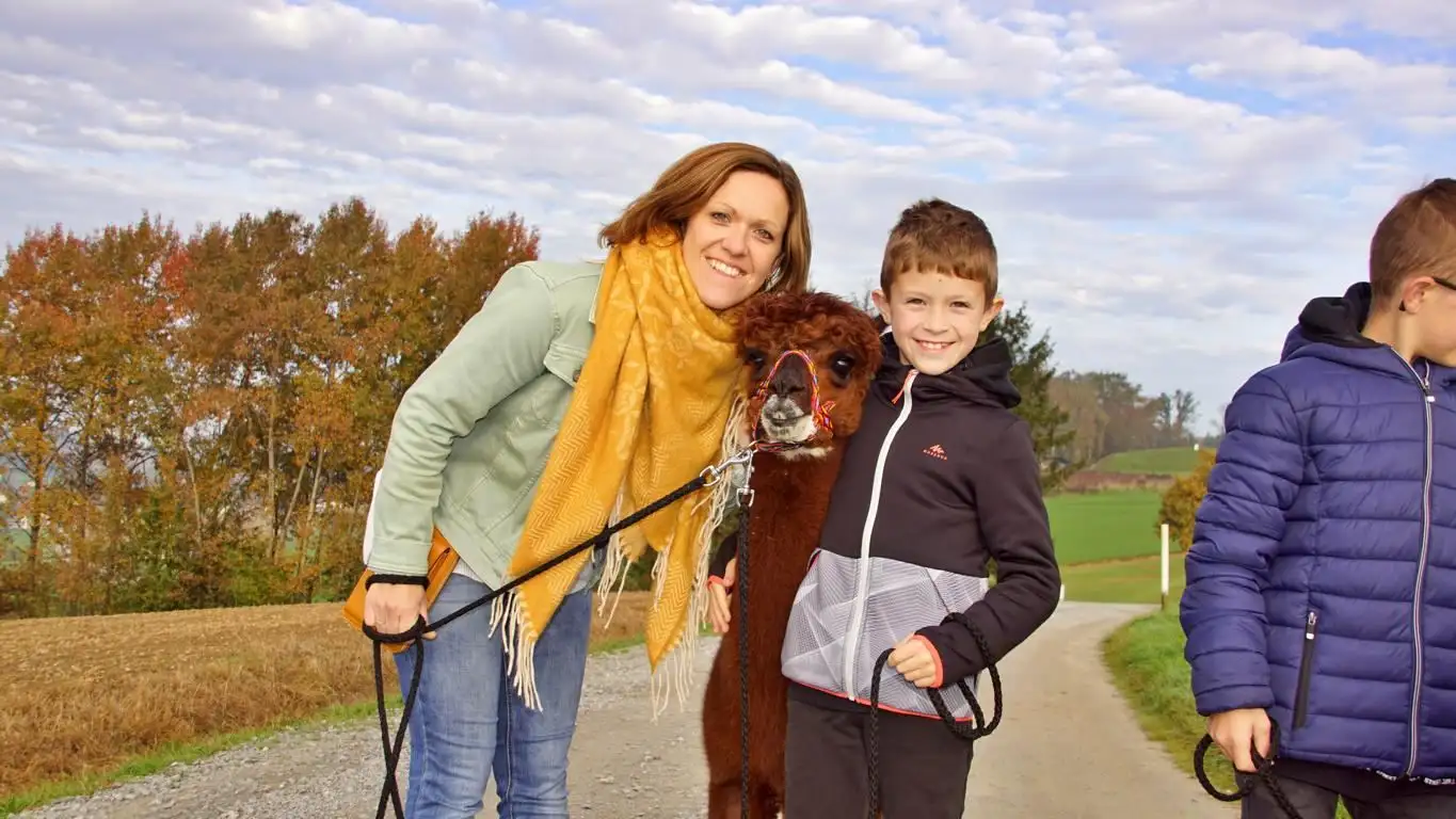 Mutter und Sohn beim Alpakwandern freudestrahlend mit unserem Alpaka "Ronaldo Schnautzbart"