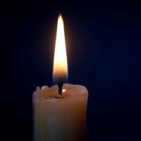 Closeup of white candle burning in the dark, candle fire on black background, selective focus